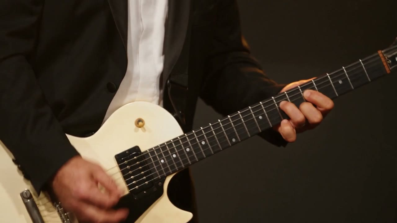 Amplified guitarist playing a white electric guitar